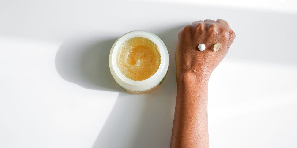 Antipollution-Skin-products-Malée-Natural-Science Antipollution Skin products Malée Natural Science an open 250ml Moisturising scrub sets next to a female hand with a dot of 75ml verdure hand cream a dot of body scrubnd a