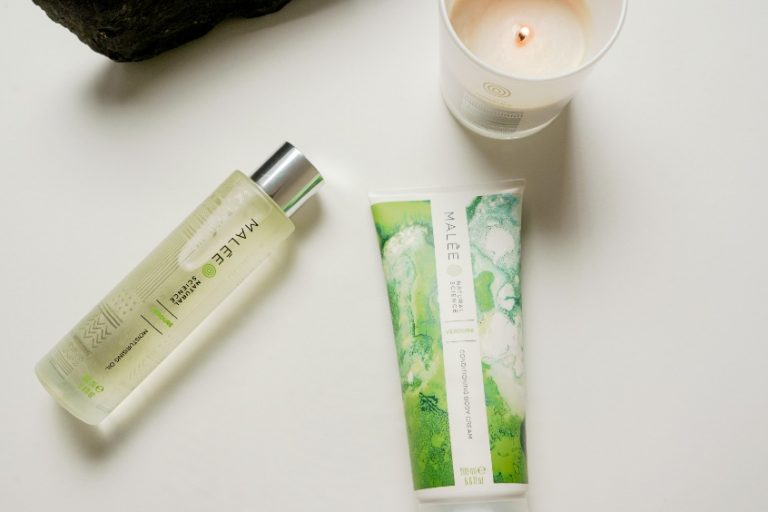 Dry Skin Rash Malee Natural Science set on a white platform, a lighted 220ml soy candle 100ml Moisturising Body Oil 200ml Conditioning Body Cream