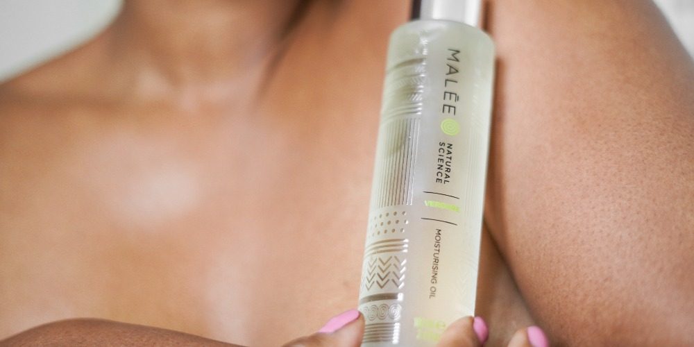 Hair Oil how to use a lady with pink nail polish is holding a 100ml Verdure Body oil close to her left shoulder