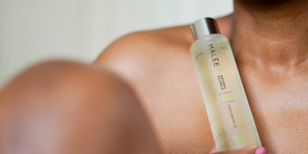 Cleansing with oil Malee Natural Science A skin toned lady is holding the 100ml Verdure Moisturising Body Oil in her hands closed bare chest