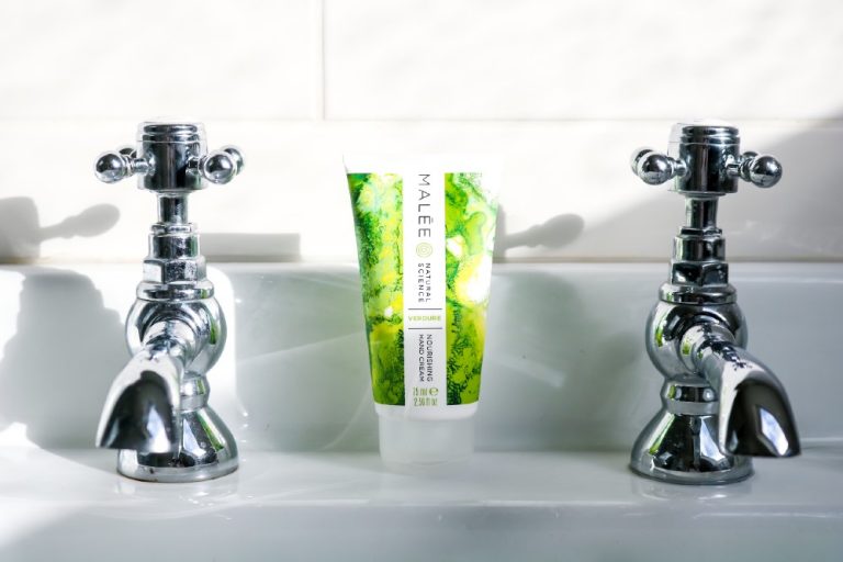 Malée Natural Science Malée's 75ml Verdure Nourishing Hand Cream placed between 2 silver taps head part with white background
