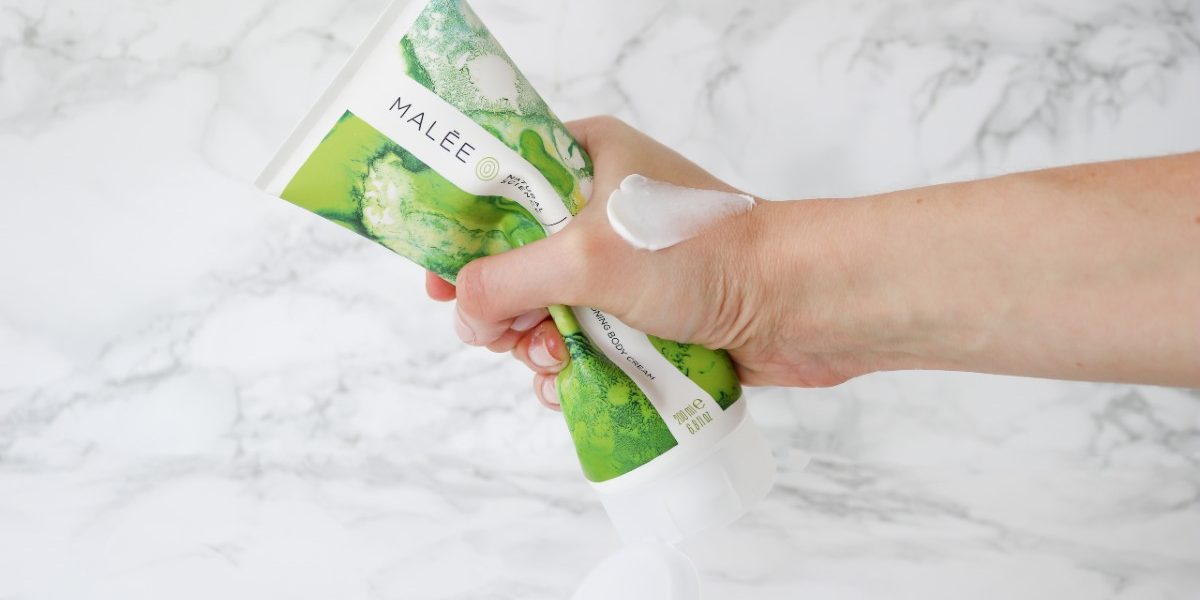 Malée Natural Science Everything you need to know about sustainable beauty products Malée Natural Science a hand gently squeezing a 200ml Verdure Conditioning Body Cream with cream on the hand