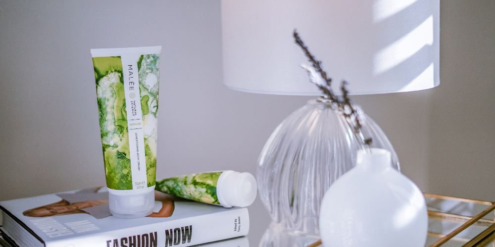 7-tips-for-Plumper-Skin-Malee-Natural-Science 7 Tips for plumper Skin Malee natural Science The 200ml Verdure Conditioning Body Cream is set along with the 75ml Verdure Hand Cream on a book name Fashion Now. Next to them, a white night lamp and a ceramic white flower pot with few lavender leaves