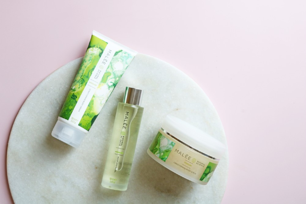 Malée Natural Science Are Fragrance Safe?75ml Verdure Nourishing Hand Cream 100ml Moisturising Oil 220g Verdure Conditioning Scrub all placed on a white board with pink bacground