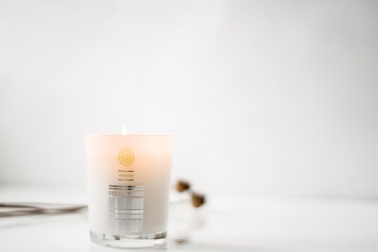 Benefits of Aromatherapy Massage Malee Natural science On a pale grey background next to some dry flowers, a lighted 220ml Verdure Soy Candle is set.