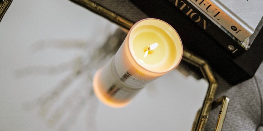 Relax-room-Malee-Natural-Science Relax Room placed on a silver and gold plate, a burning Verdure Soy Candle. Aside few books