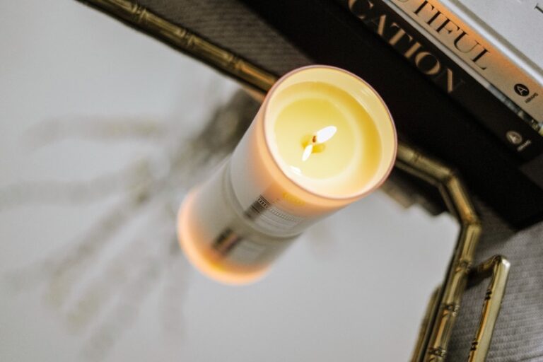 Relax Room placed on a silver and gold plate, a burning Verdure Soy Candle. Aside few books
