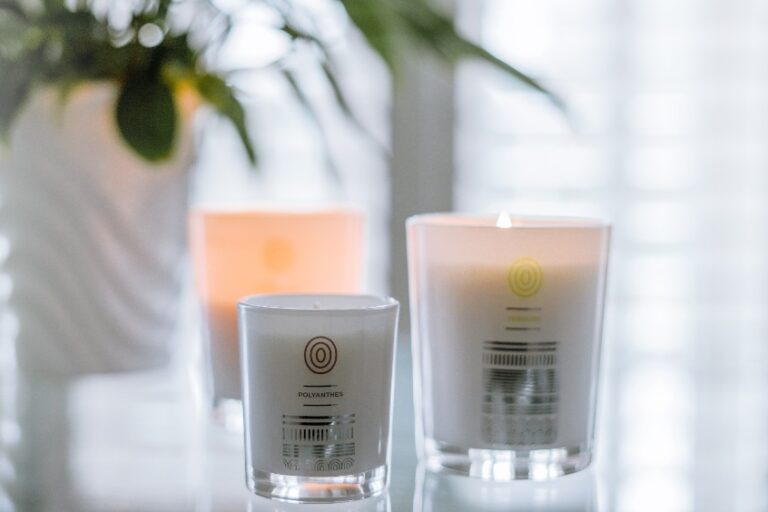 Aromatherapy with candles Malee Natural Science, Set on a glass table, a lighted 220ml Verdure Soy Candle, a ceramic pot of green indoors plant and a 220 Polyanthes Soy Candles